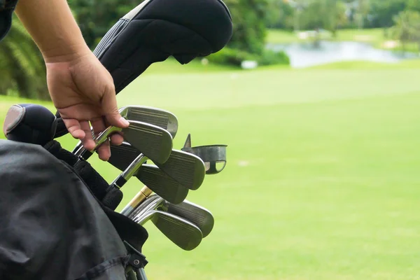 Set of golf clubs over green field background