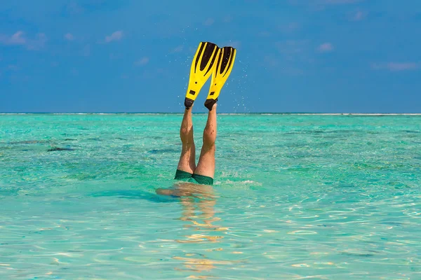 Men dive snorkeling in clear water on the beach Islands with yellow flippers