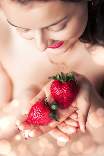 Photo of seductive female holding strawberry near face lips, closeup portrait redhead sensual woman biting berry