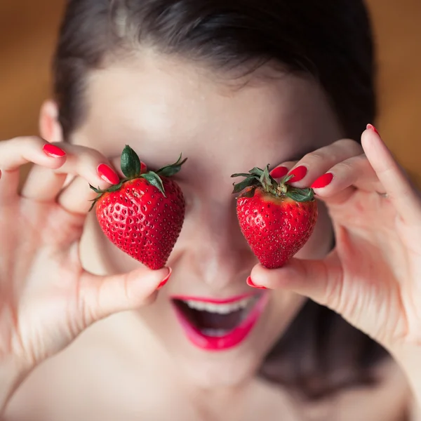 Photo of seductive female holding strawberry near face eyeys, closeup portrait redhead sensual woman biting berry