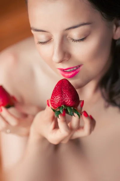 Photo of seductive female holding strawberry near face, closeup portrait redhead sensual woman biting berry