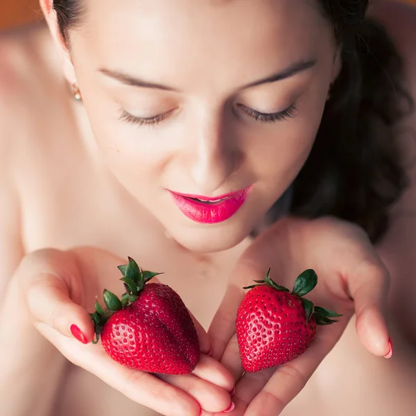 Photo of seductive female holding strawberry near face lips, closeup portrait redhead sensual woman biting berry