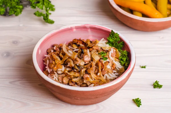 Mujadarra - arabian dish with rice, lentils and onion on wooden background. Ramadan food. Eastern cuisine. Selective focus