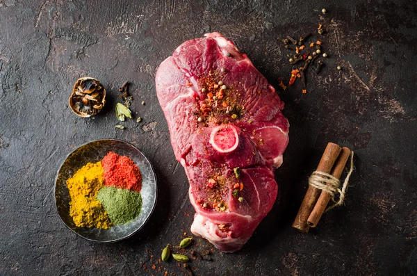 Raw Mutton meat with east spice on dark background.