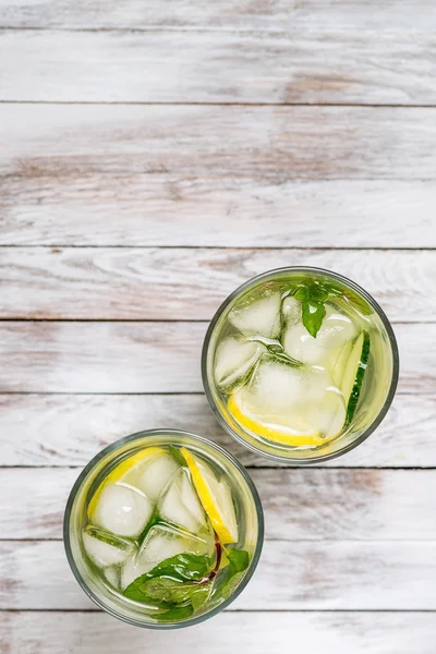 Water with lemon, mint and cucumber on wooden light background. Water Detox. Top view.