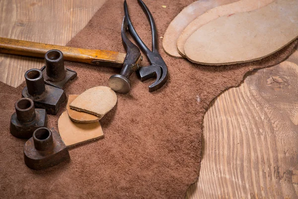 Set of leather craft tools on wooden background. Workplace for shoemaker.