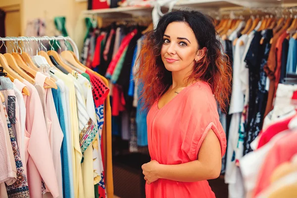 Young pretty woman shopping in women store. Looking to the camera. Shopping time. Summer sale.