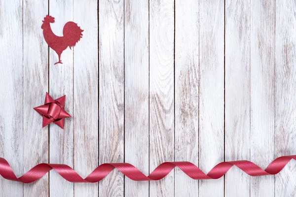 Rooster, star, ribbon on wooden background. Winter holidays concept. New Year of rooster.