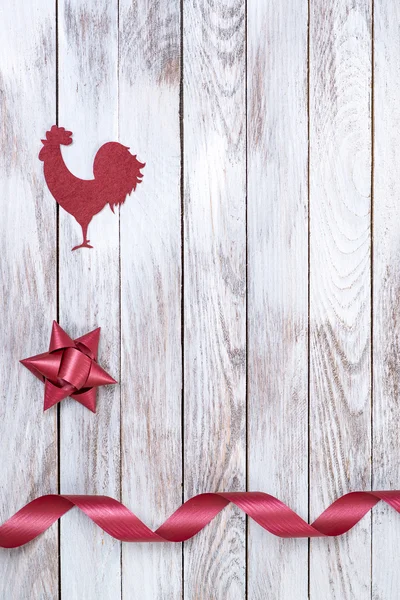 Rooster, star, ribbon on wooden background. Winter holidays concept. New Year of rooster.