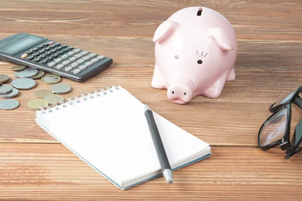 Home savings, budget concept. Model house, notepad, pen, calculator and coins on wooden office desk table.