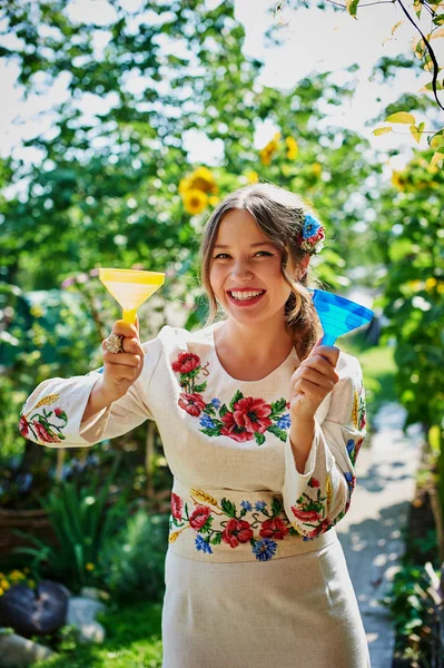 Smily girl in embroidered dress with blue and yellow funnels in her hands