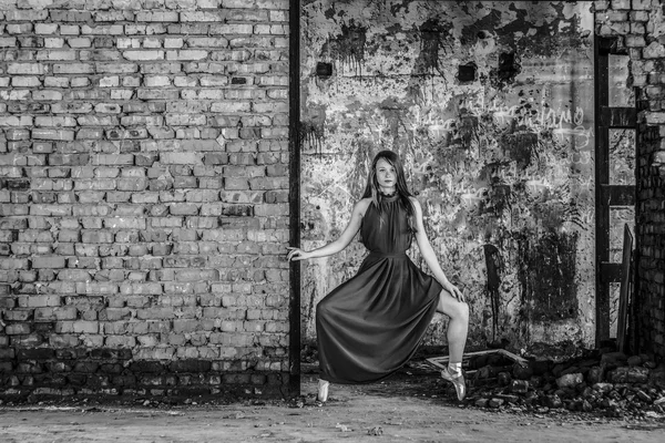 Thin slim girl with freckles on background of wall of destroyed building. Black and white photo