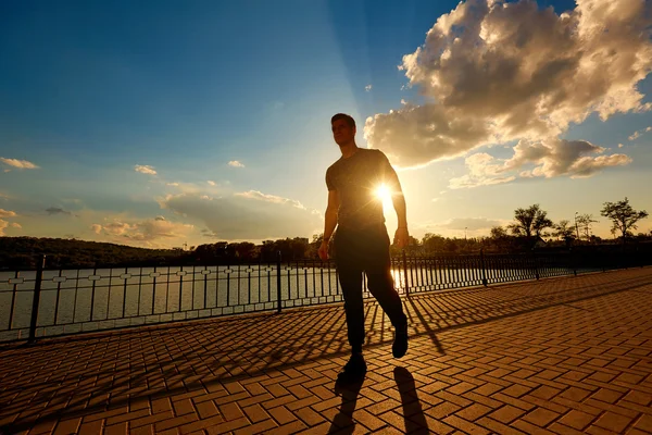 Athletic man after jogging in the rays of the evening sun. Sport