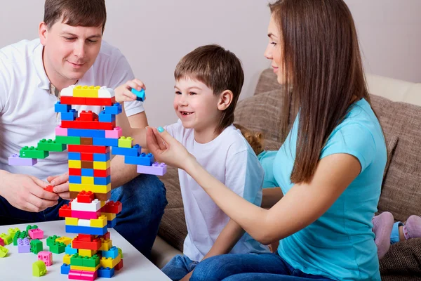 Happy family  playing with colorful blocks inside at home.