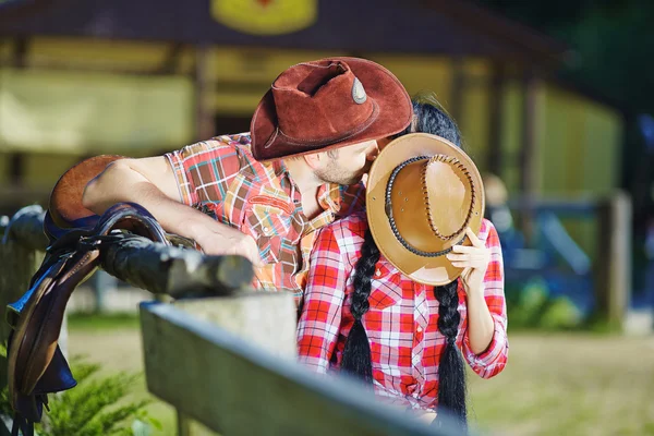 Cowboy couple kissing a guy and girl in cowboy hats.