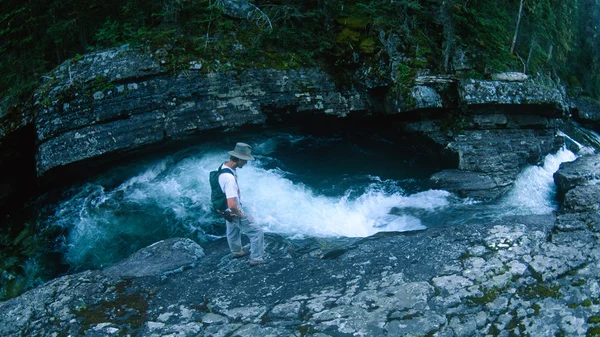 Man Standing Over a High Fast Moving Mountain Stream