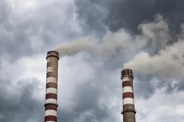 Smoking industrial chimneys in dark clouds. Concept for environmental protection