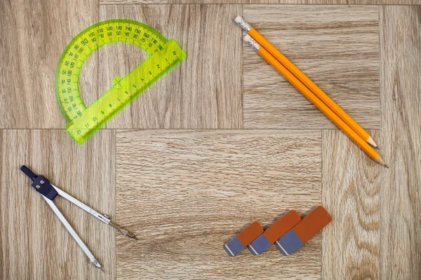 Pencil, eraser, circinus and protractor ruler on a wooden texture