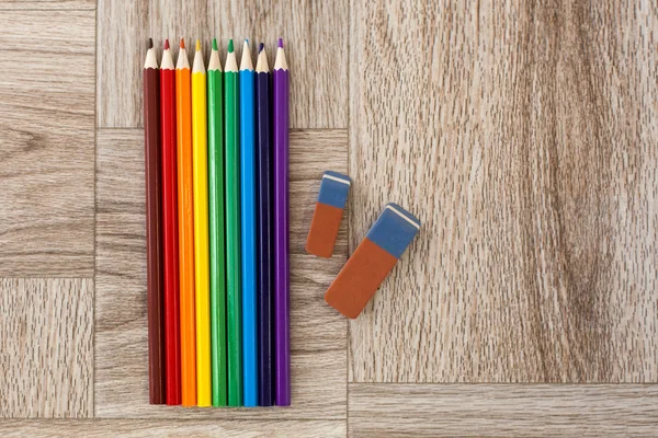Lots of assorted colors pencils and erasers on wooden background