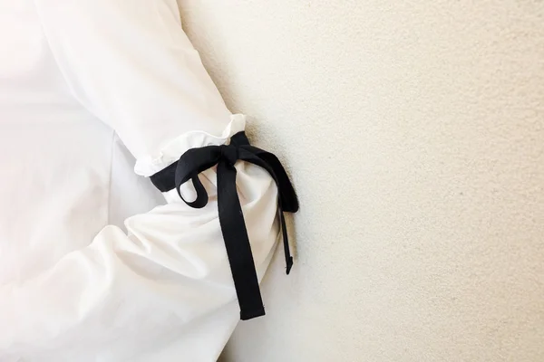 Long white sleeve with black string bow tie style details. Close up trendy fashion.