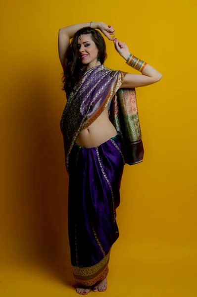 The young dark-haired woman in a beautiful Indian sari stands barefoot