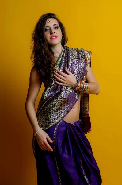 The young dark-haired woman in a beautiful Indian saris and colorful bracelets. Indian style.