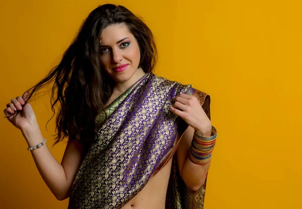 The young dark-haired woman in a bright Indian sari smiling holding arm hair strand. Indian style.