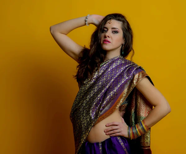 The young dark-haired woman in a bright Indian saris and colorful bracelets raised her hand to the head. Indian style.