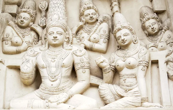 Sculptural images of Shiva and Parvati in accompaniment of the retinue on the wall of an ancient Indian temple