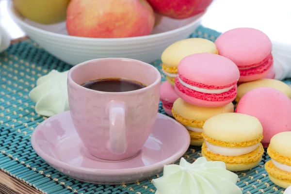 Composition of pink coffee cup and macaroon cookies