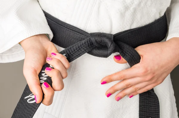 Hands with nail polish of a girl with a black belt in martial arts, close up