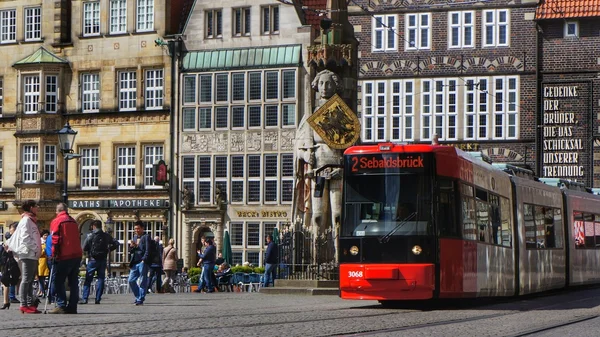 Tram trolley of the local company for public transportation passing the market square with the famous statue of \'Roland von Bremen\' (\'Roland of Bremen\')