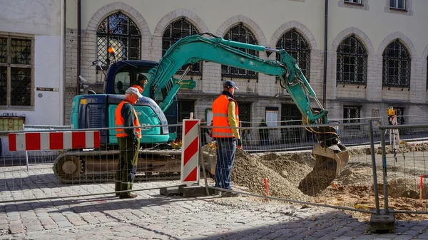 Construction workers using an excavator for preparation of street in pedestrian zone for reparation