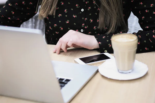 Business woman is wearing black shirt in the cafe and typing something