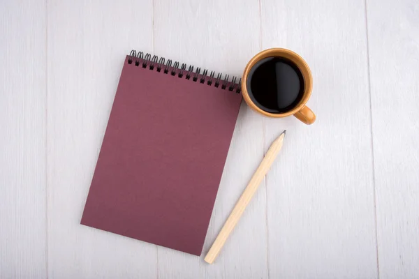 Cup of coffee, Burgundy notebook, pencil, overhead view
