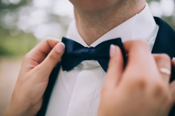 Bride fixing groom`s bow-tie