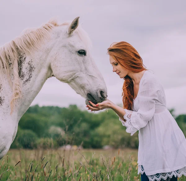 Woman feeding white horse