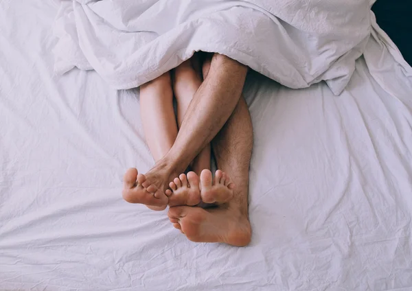 Feet of couple side by side in bed