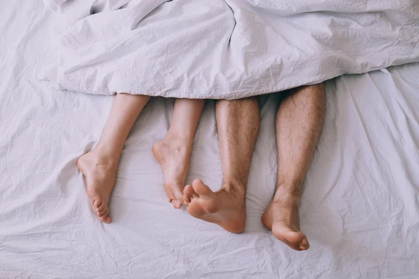Feet of couple side by side in bed