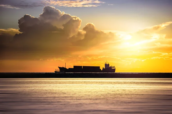 Cargo ship in the ocean at sunset sky
