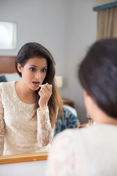 Beautiful woman making up in front of the mirror