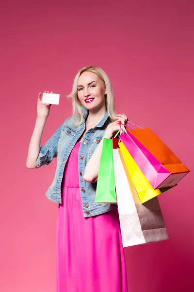 Shopping woman holding shopping bags l on pink background .