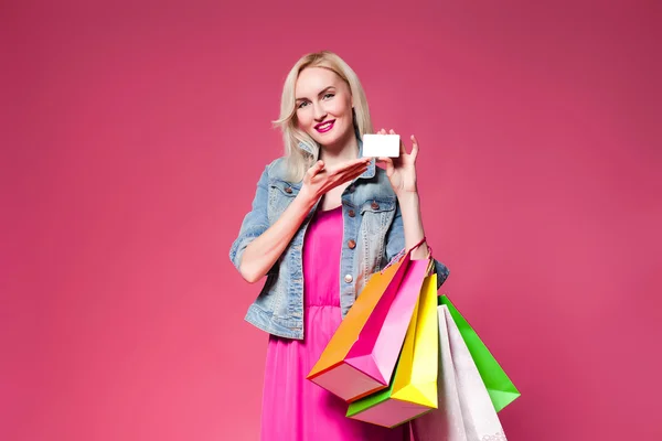 Shopping woman holding shopping bags l on pink background .