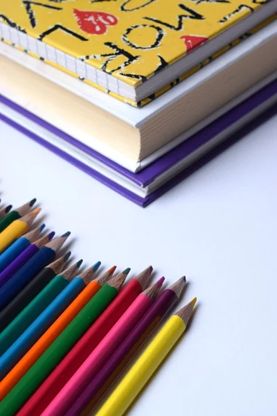 Pencils rainbow line with pile of books.