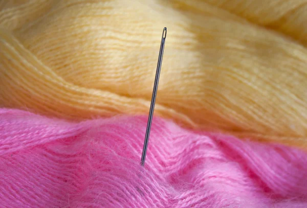 Needle and wool thread. Pink and yellow thread