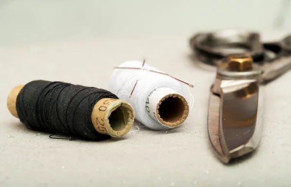 Sewing textile or cloth. Work table of a tailor. Scissors reel of thread, and natural fabric. . Shallow depth of field. Focus on scissors. Top view