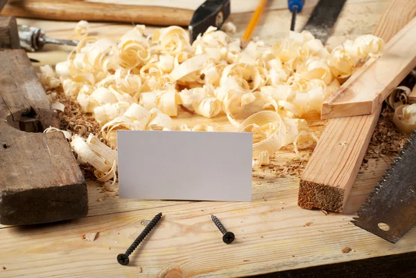 Business card on wooden table for carpenter tools with sawdust.