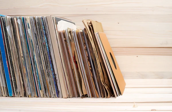 Retro styled image of a collection of old vinyl record lp\'s with sleeves on a wooden background.  Copy space