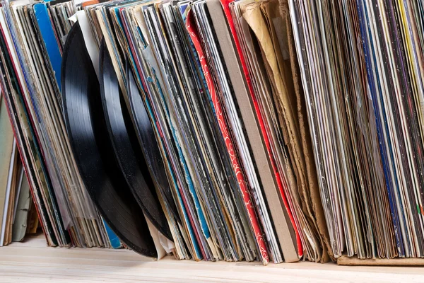 Retro styled image of a collection of old vinyl record lp\'s with sleeves on a wooden background. Browsing through vinyl records collection. Music background. Copy space