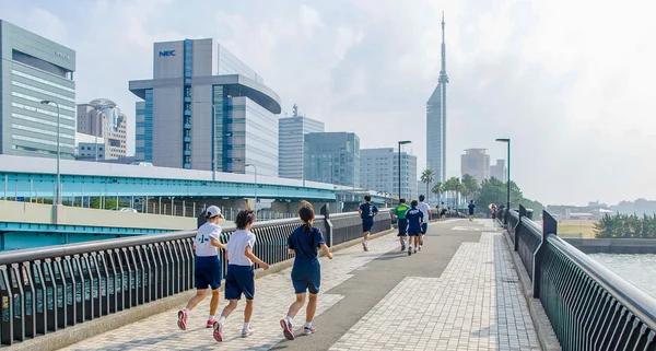 Fukuoka, Japan - June 30, 2014: Japanese high school students running in Momochi Beach road.This road heading to Fukuoka tower